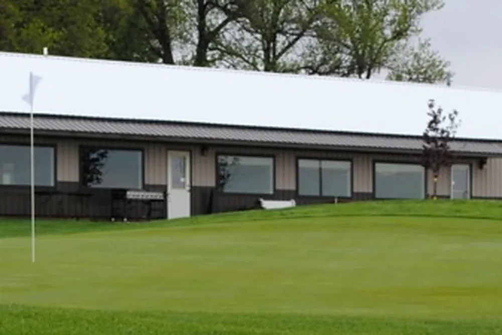 The Meadow Acres clubhouse looking out over a green with the flag in