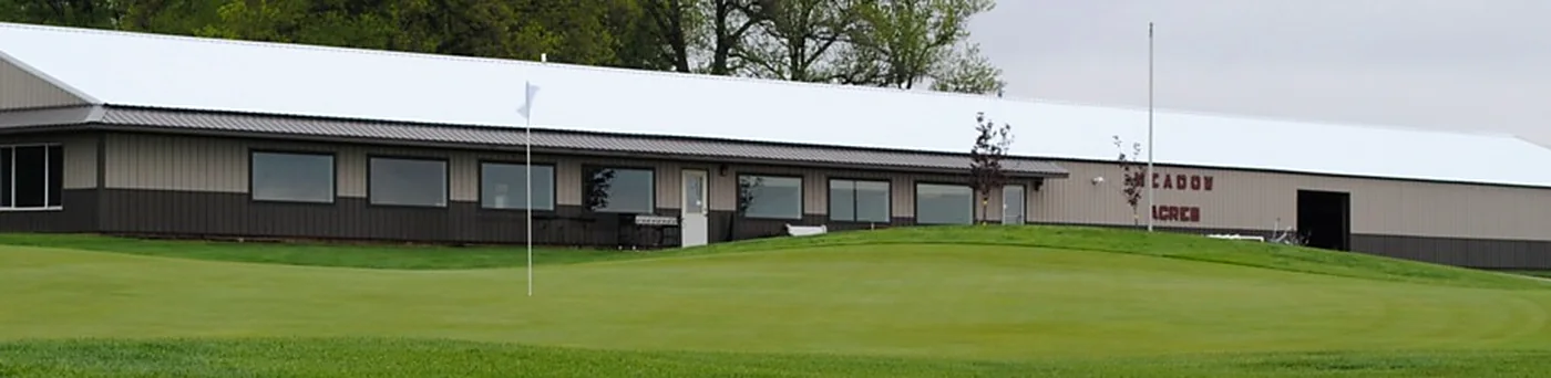 The clubhouse behind a green with the flag flying